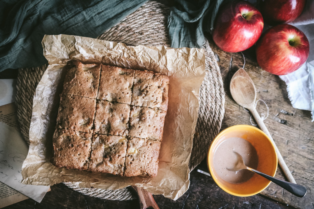overhead view of apple blondies next to a bowl of apple glaze and fresh apples.