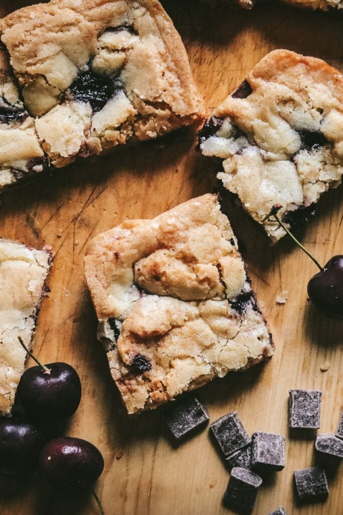 overhead view of crackly, golden brown cherry chocolate blondies next to chocolate chunks and fresh cherries.