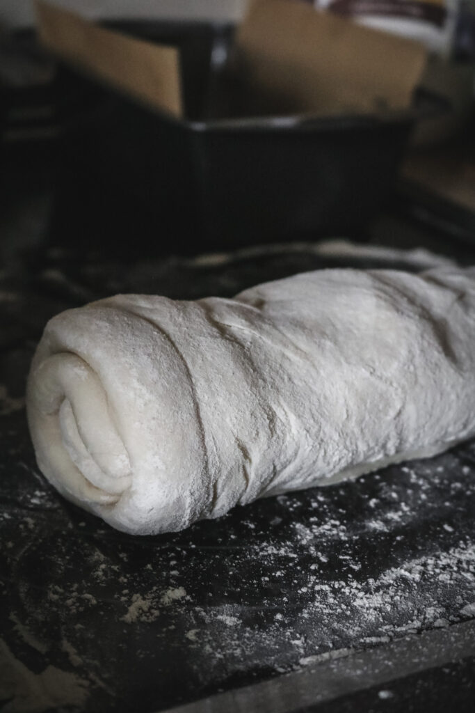 close up view of homemade bread dough rolled up into a spiral in part of the shaping process.