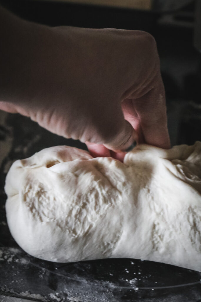 pressing the long sides of bread dough together and pinching the seams as the final part of shaping sandwich loaves.