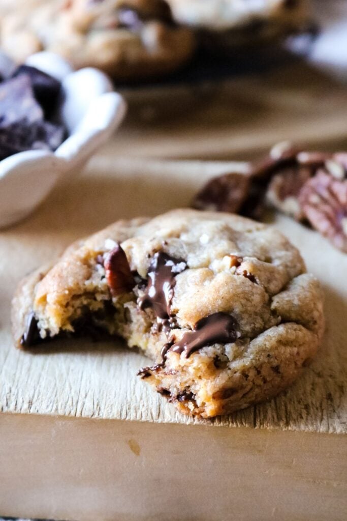 close up view of a large 4 ounce chocolate chip and pecan cookie with molten chocolate pockets and chunks of pecans sticking out of the top.
