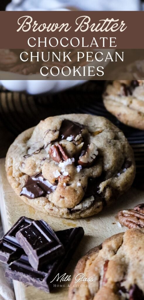 a tall pin with a close up image of a large cookie with lots of dark chocolate chunks and toasted pecans surrounded by ingredients on a wooden cutting board.