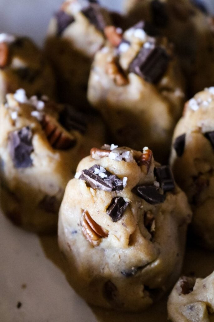 close up view of a tall tower-shaped cookie dough chunk with dark chocolate, pecan, and flaky sea salt.