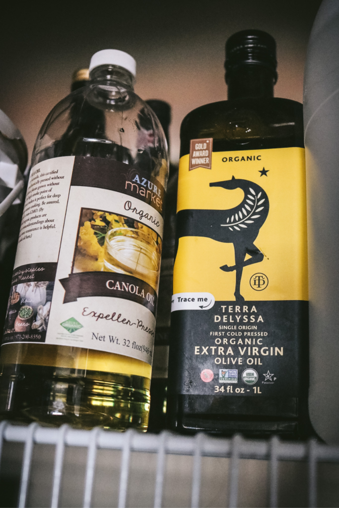 close up view of organic olive oil and canola oil in a pantry.
