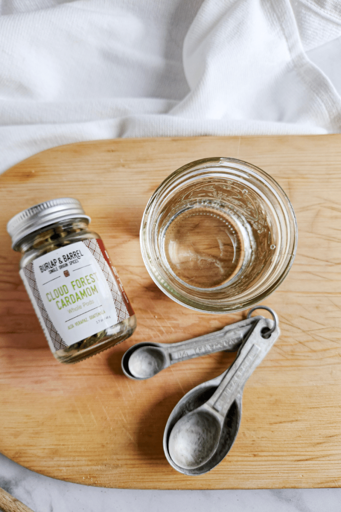 overview of a bottle of cardamom pods and a jar of vodka to make cardamom extract.