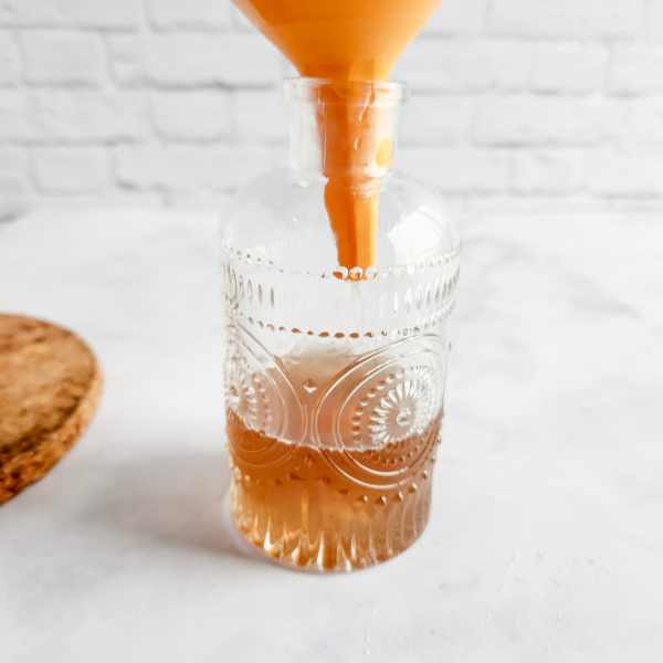 straining lavender syrup into a glass bottle.
