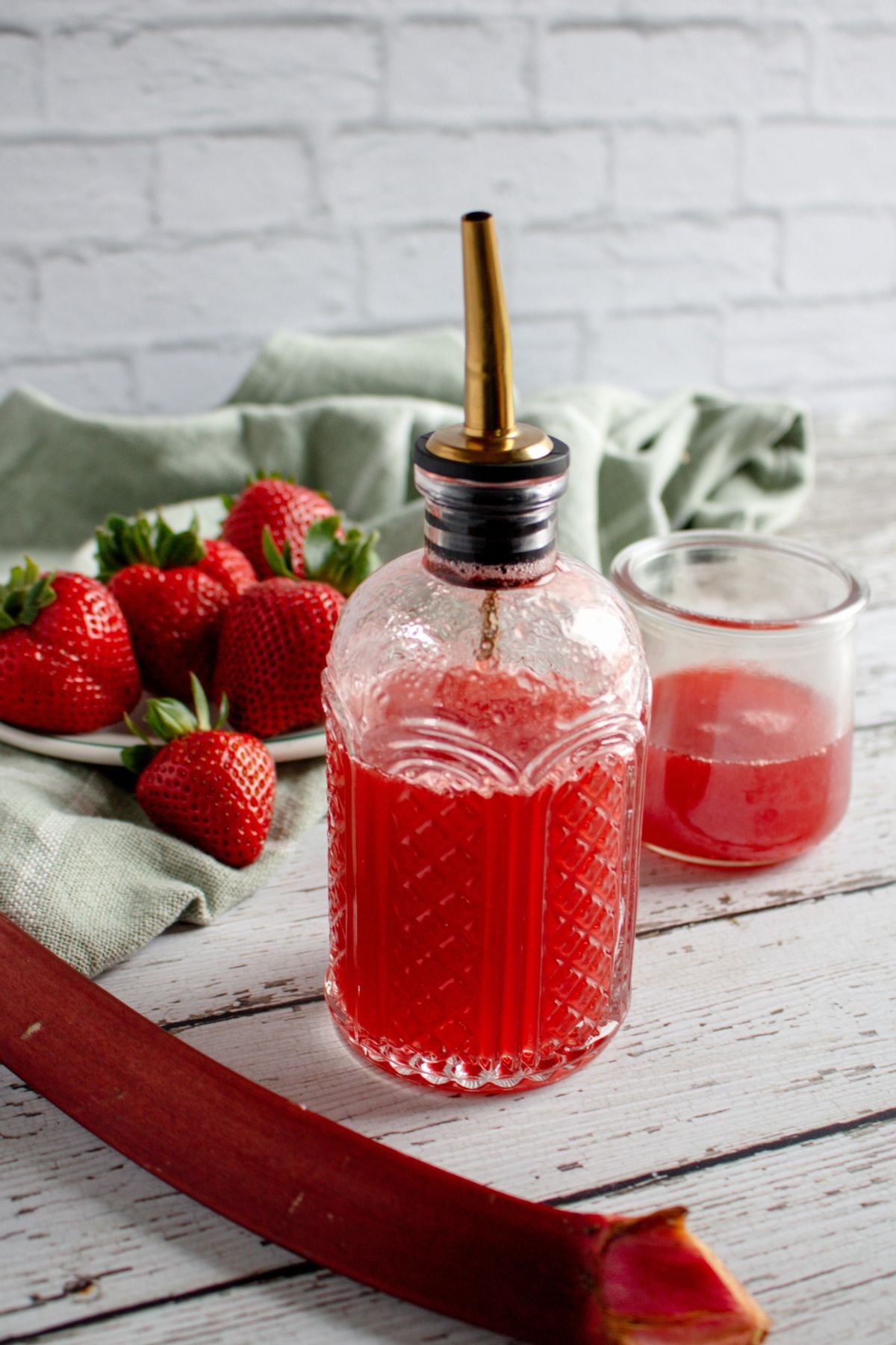 side view of a glass bottle with homemade strawberry rhubarb simple syrup.