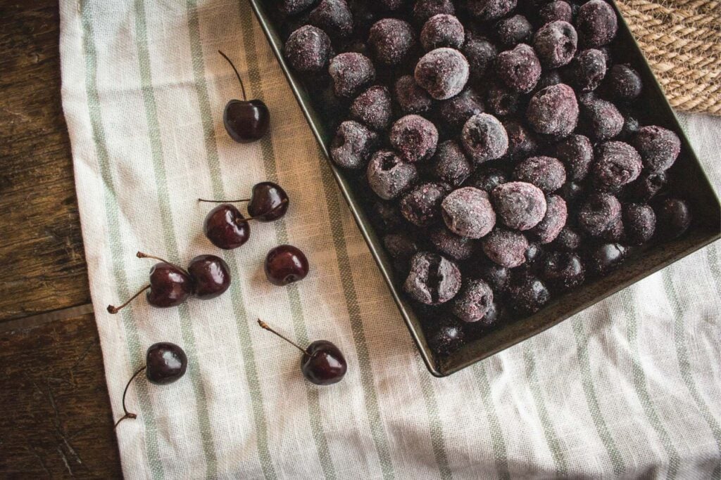 vintage tray of frozen cherries on a white and green tablecloth.