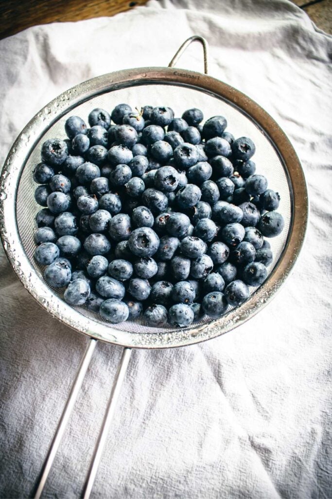 rinsing fresh blueberries in a strainer.