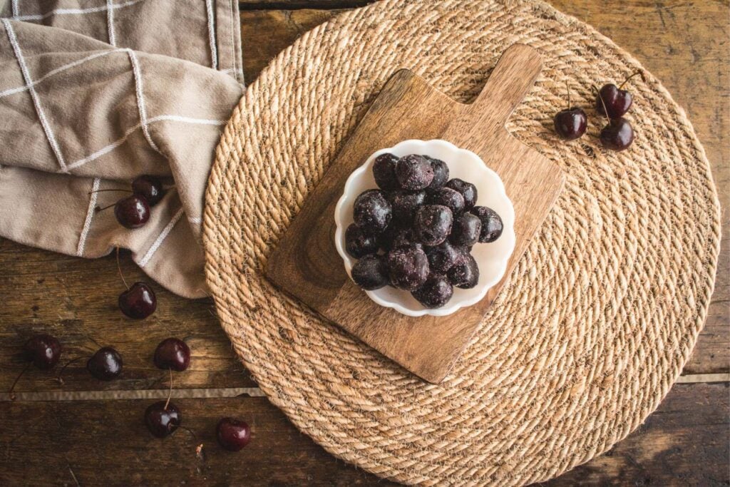 overhead view of a small scalloped bowl full of frozen cherries.