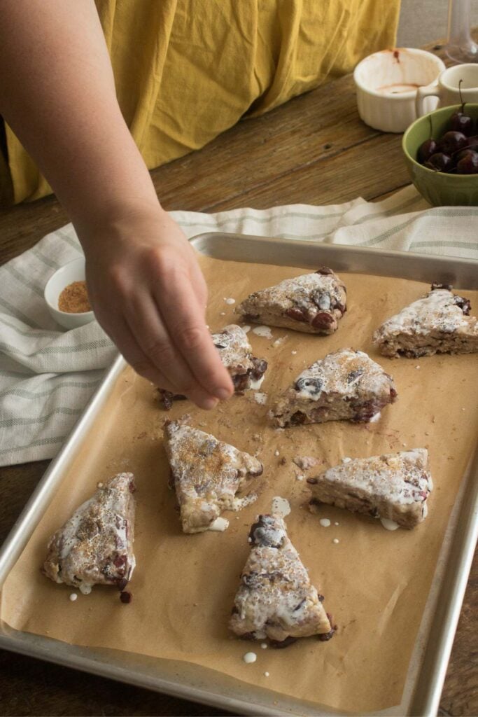 sprinkling sugar on cherry scones before baking.