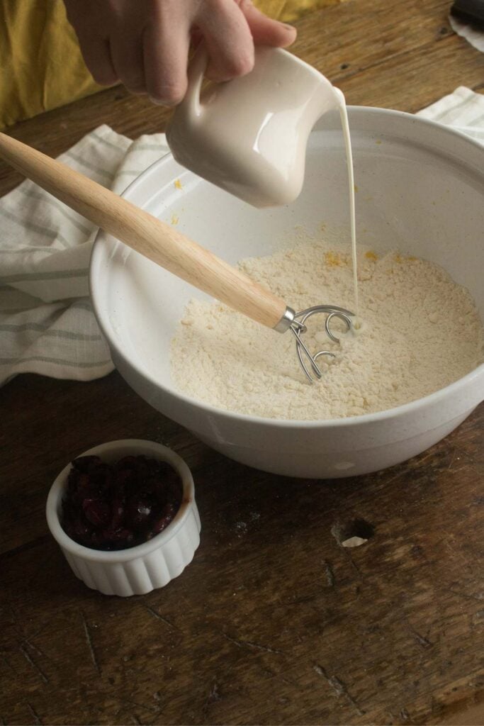 pouring cream into scone dough.