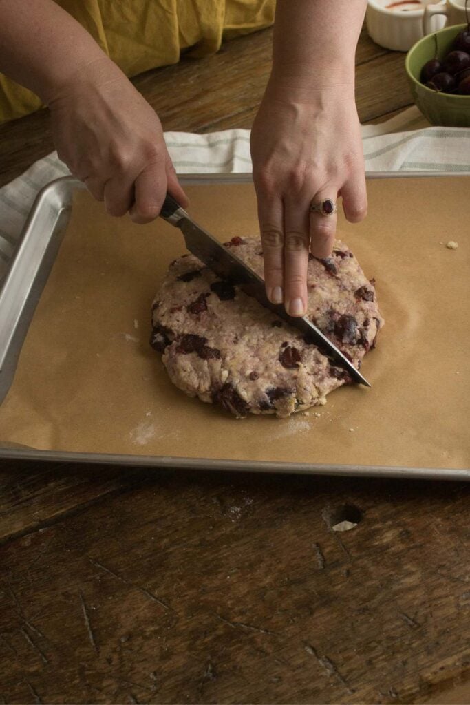 cutting fresh cherry scones into slices.
