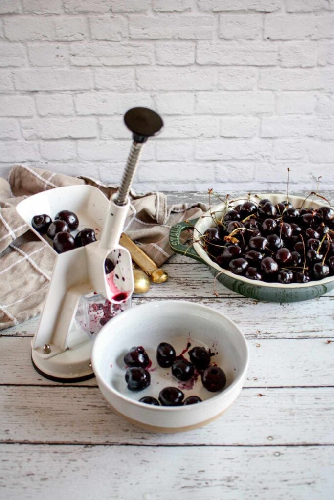 pitting fresh cherries on a light wood surface.