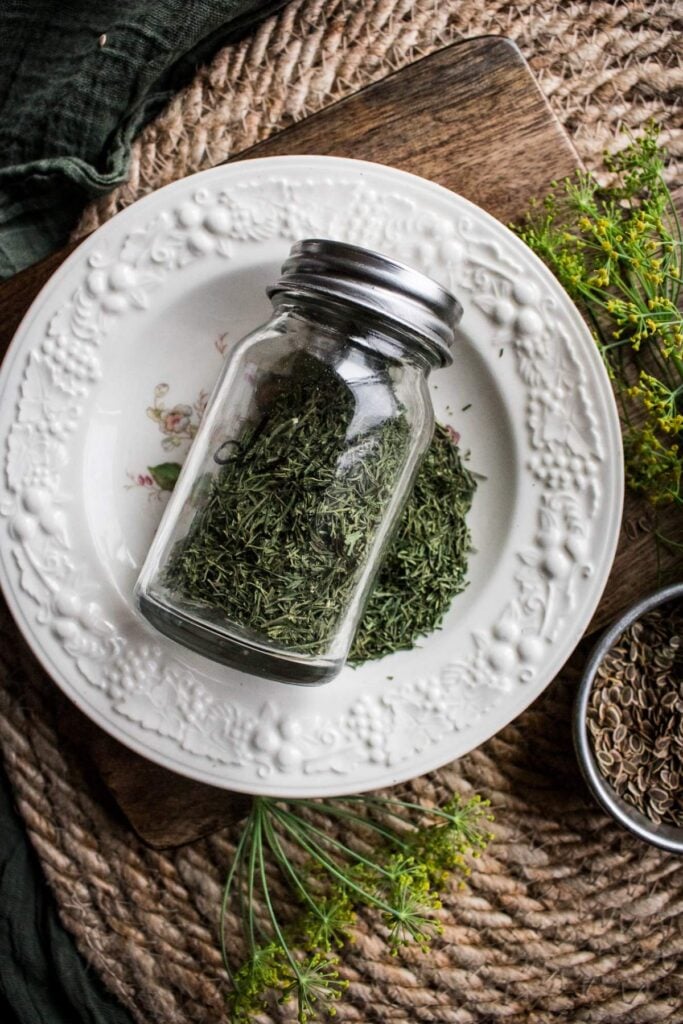 glass spice jar of dried dill on a vintage bowl.