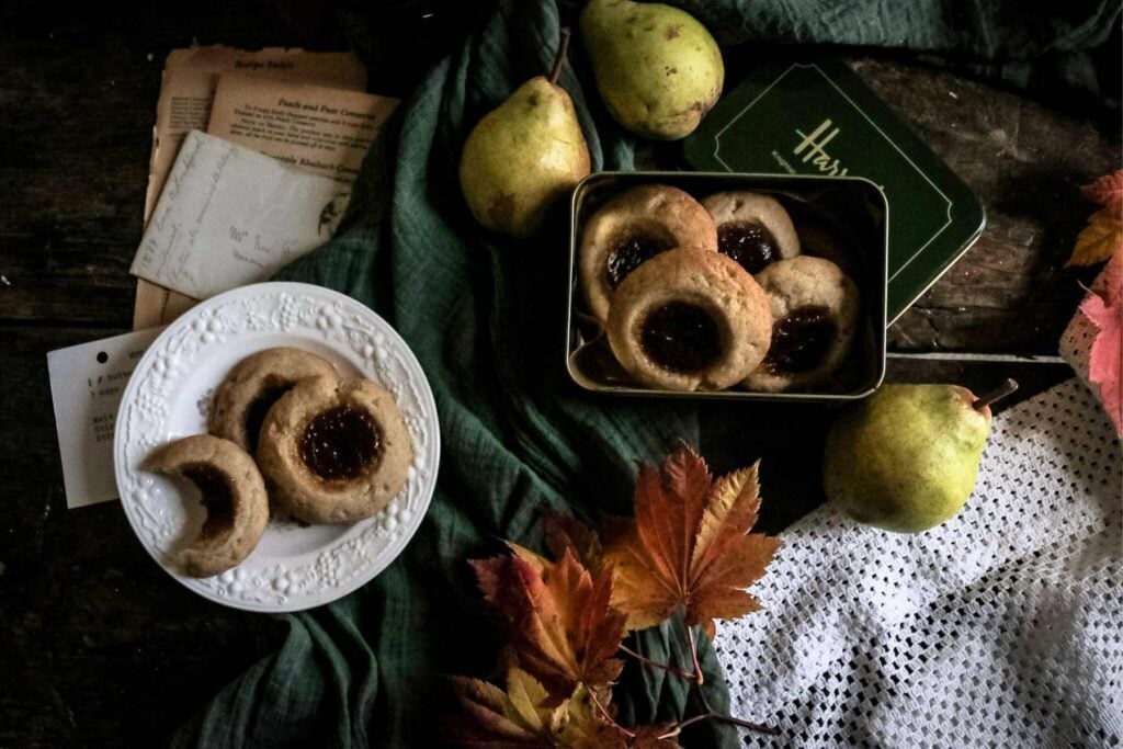 white plate with pear butter thumbprint cookies by fall leaves.