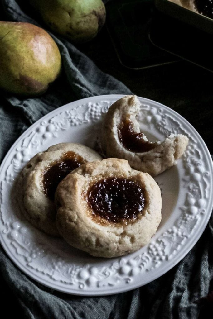 tall image of pear butter thumbprint cookies on a white plate.