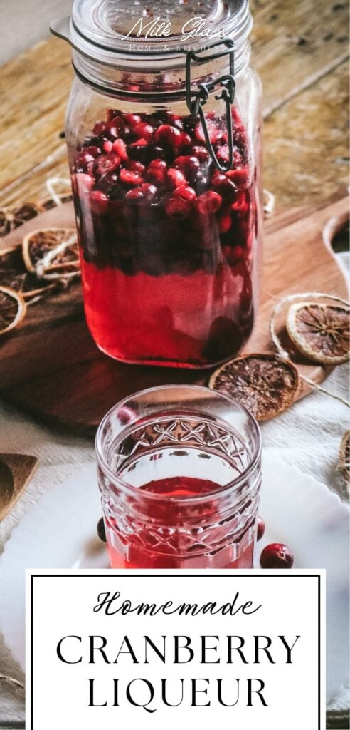 large glass jar with homemade cranberry liqueur made with fresh cranberries.