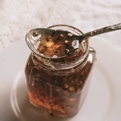 glass jar of homemade hot honey with a vintage spoon on top.