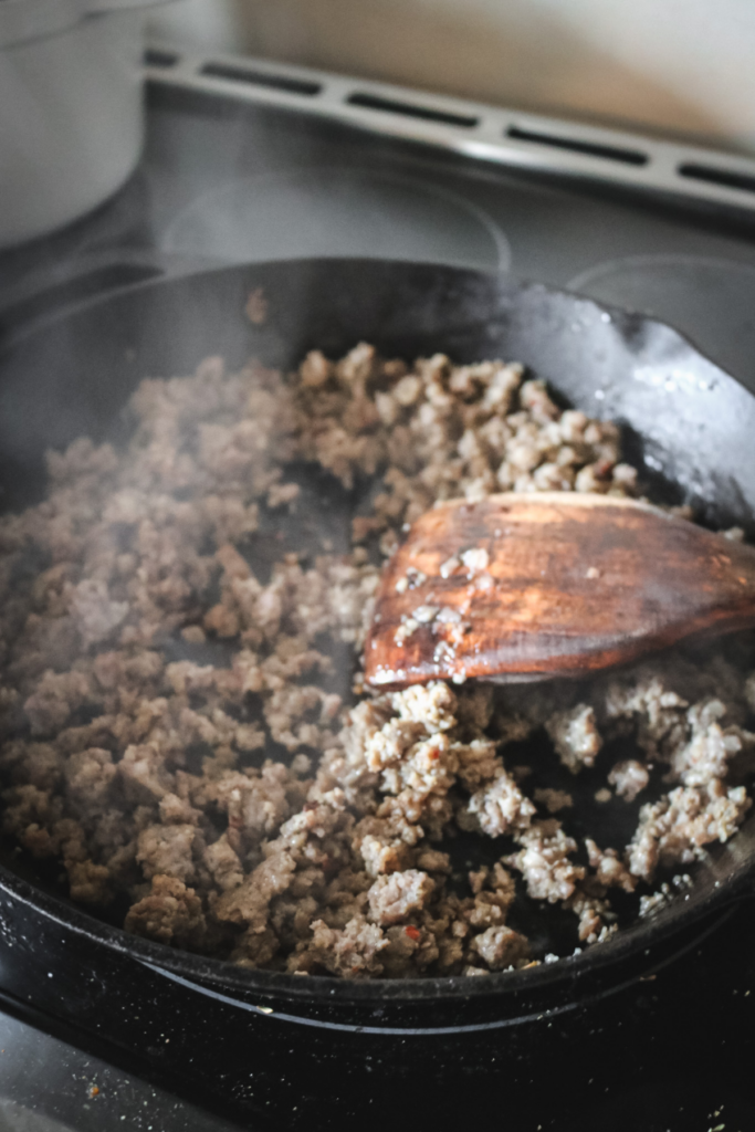browning sage sausage in a cast iron skillet.