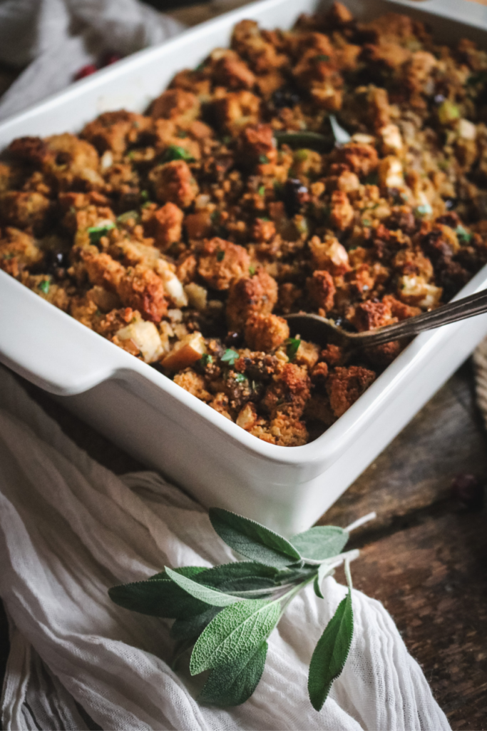 serving sourdough cornbread stuffing out of a baking dish with a vintage spoon.