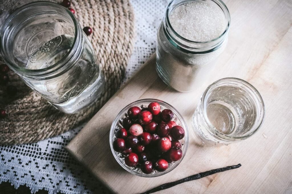 mason jars with vodka, water, sugar, cranberries, and a vanilla bean.