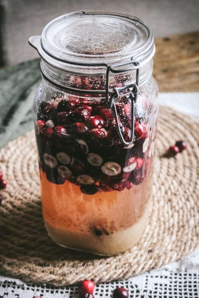 large glass jar with homemade cranberry liqueur.