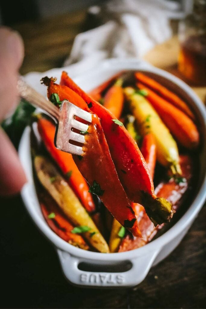 spearing roasted hot honey carrots with a fork.