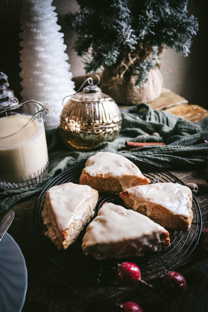 set of 4 eggnog scones cooling next to a pitcher of eggnog.