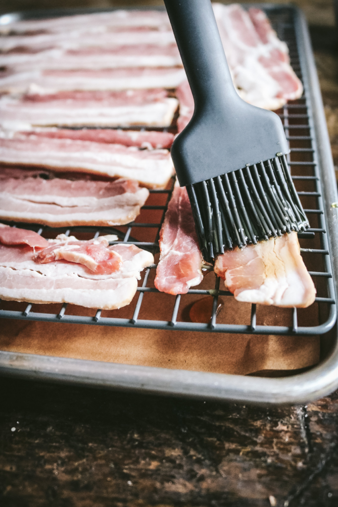 brushing bacon with maple syrup.