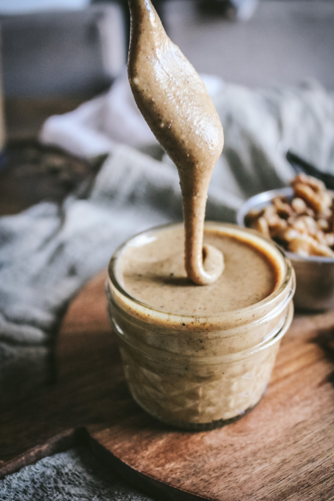 close up view of walnut butter dripping off a spoon.