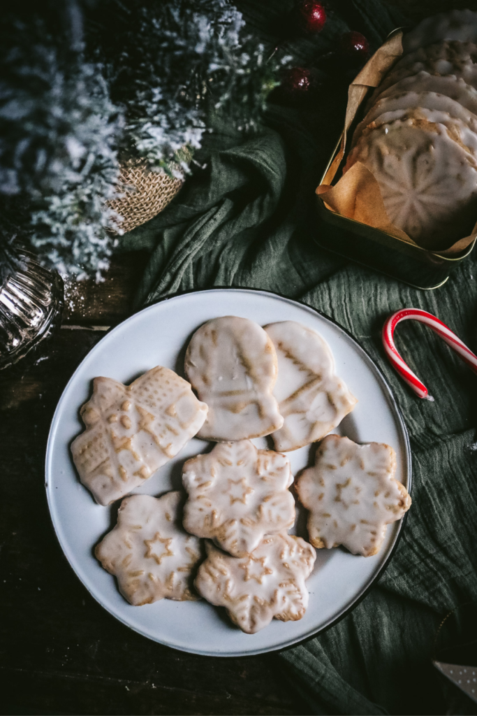 white enamel plate with homemade honey gingerbread next to a candy cane.