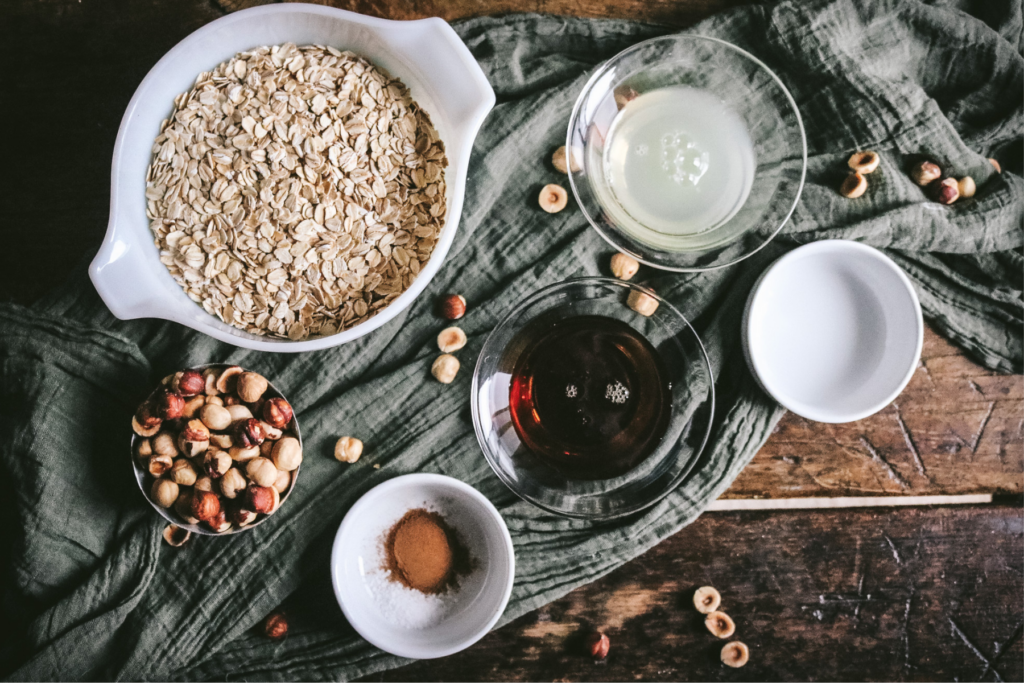 overhead view of the ingredients for hazelnut granola including oats, hazelnuts, maple syrup, egg whites, and more.