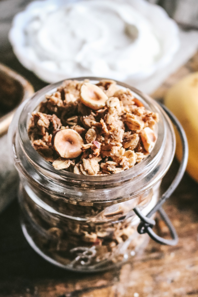 vintage mason jar with homemade hazelnut granola by a banana and yogurt.