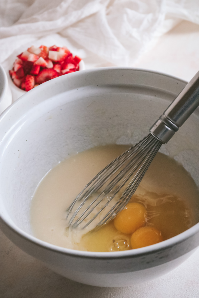 medium mixing bowl with wet ingredients and eggs.