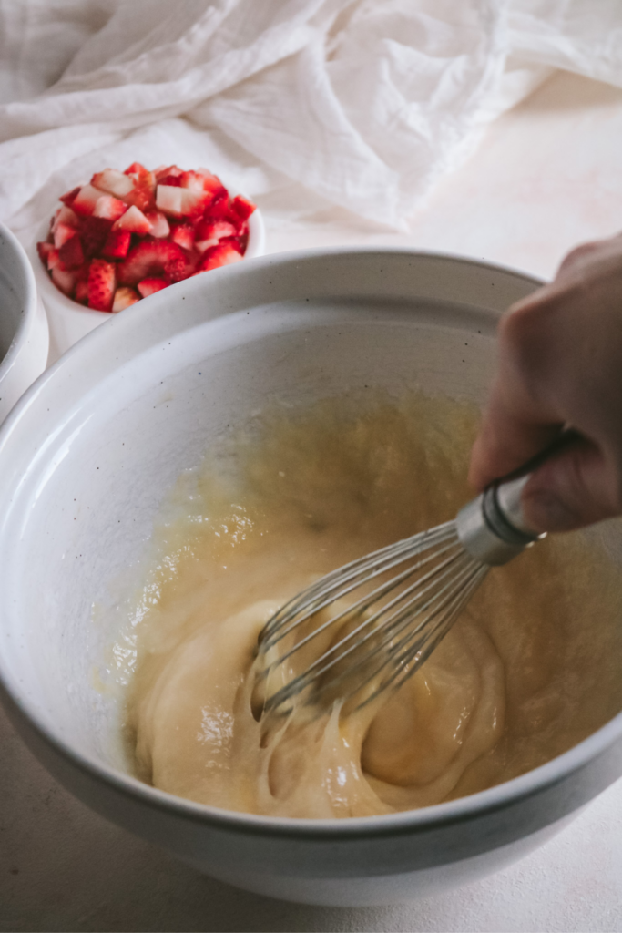 whisking the wet ingredients together to make strawberry muffin batter.