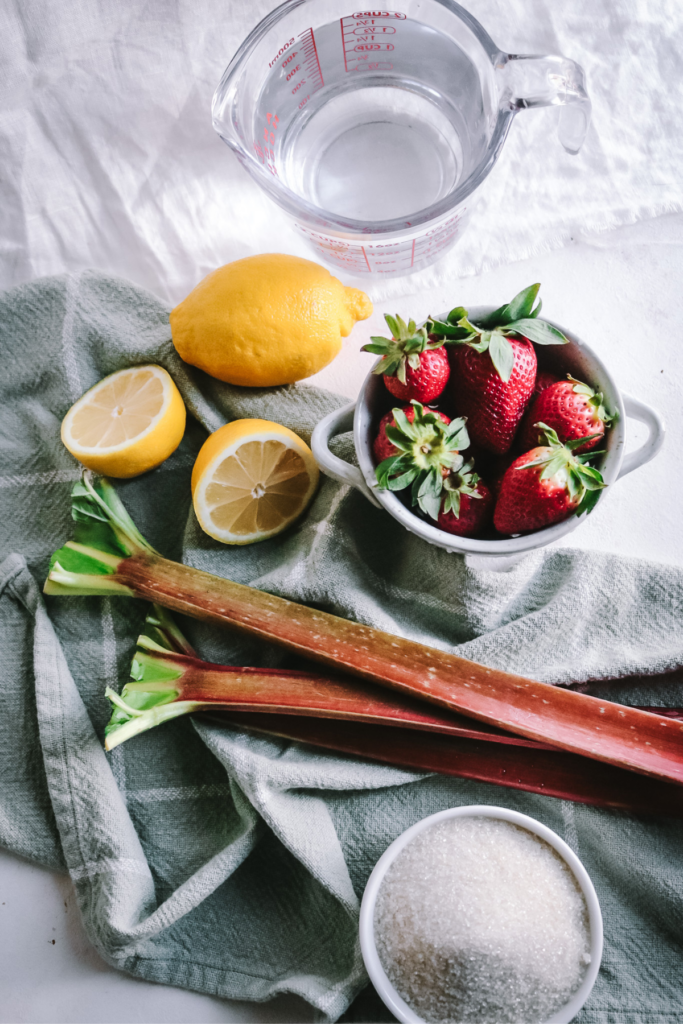 surface with sugar, water, lemons, rhubarb, and strawberries to make strawberry rhubarb lemonade.