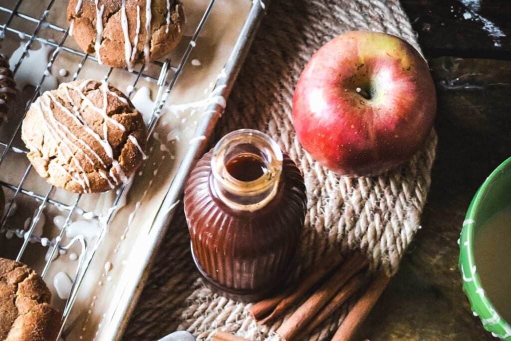 overhead view of apple cider syrup next to apple cider cookies.