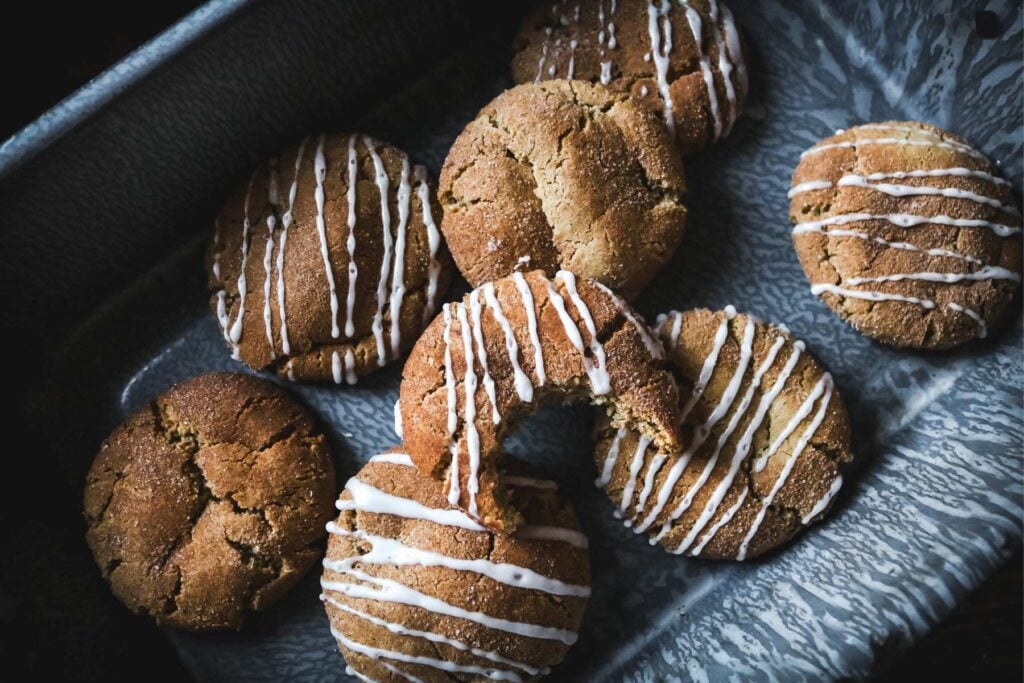 overhead view of a graniteware baking pan with warm, chewy apple cider crinkle cookies topped with an apple glaze.