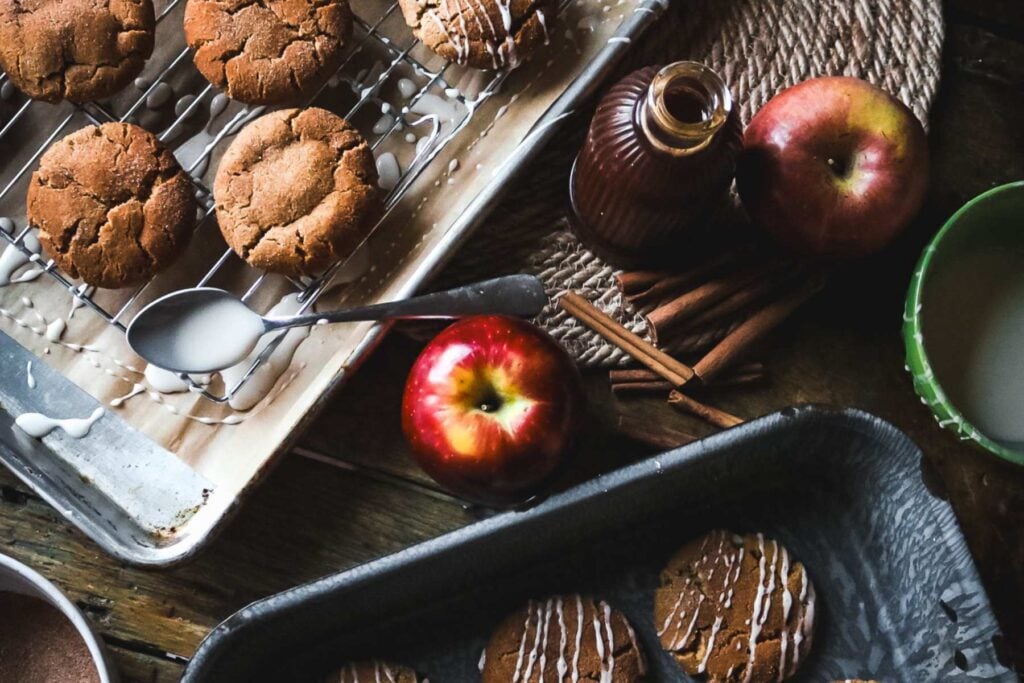overhead view of a tray with glazed apple cider cookies next to a cooling rack with unglazed cookies ready to ice.