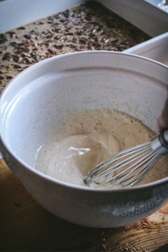 whisking liquids for cobbler batter with pecan pie filling in the back.