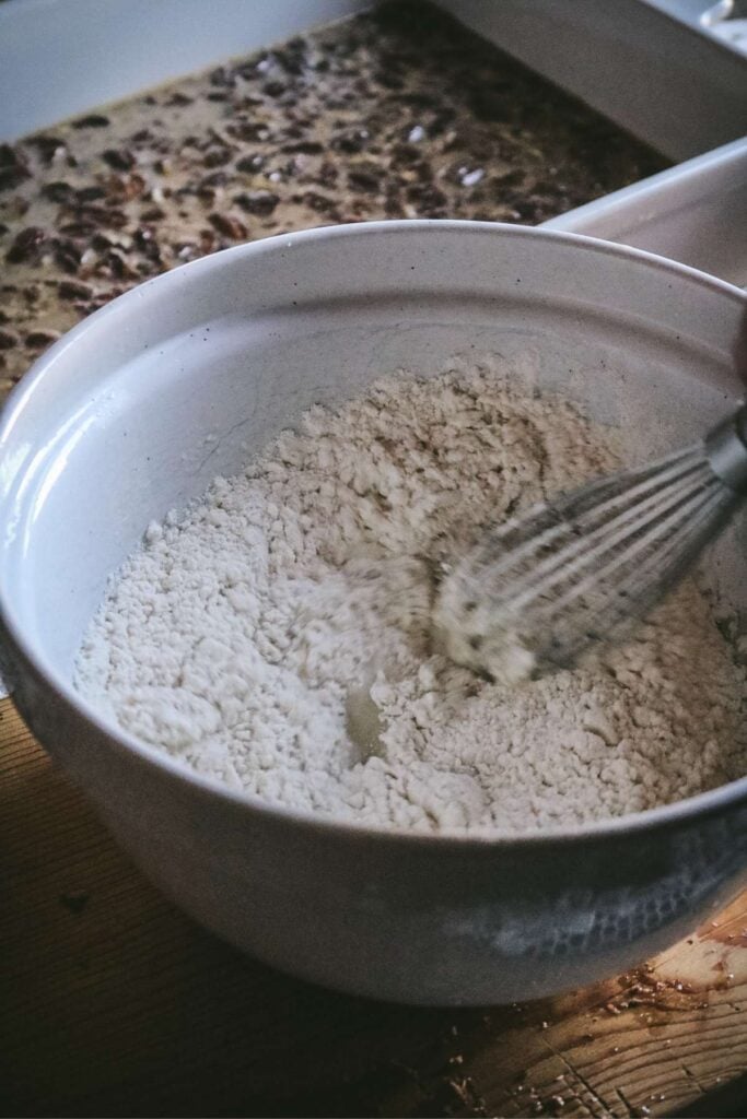 whisking in the dry ingredients for pecan pie cobbler.