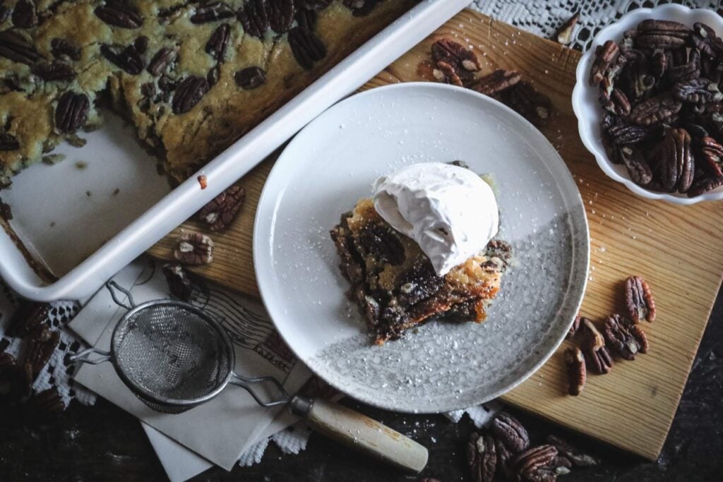 overhead view of a tray of pecan pie cobbler next to a plate.