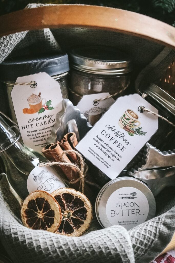 closeup view of different homemade christmas gifts like christmas coffee, hot cocoa mix, caramel milk mix, spoon butter, a beeswax candle, and more.