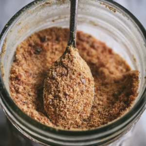 close up view of homemade caramel sugar in a glass jar with a spoon scooping some up.