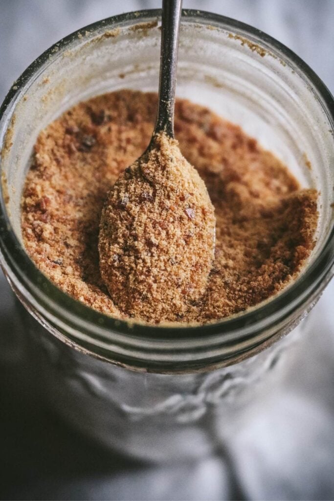 close up view of caramel sugar on a spoon in a mason jar.