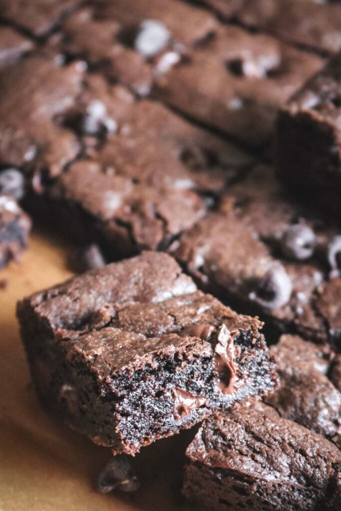 close up view of a chocolate chocolate chip cookie bar with melted chocolate chips in it set on top of other bars.