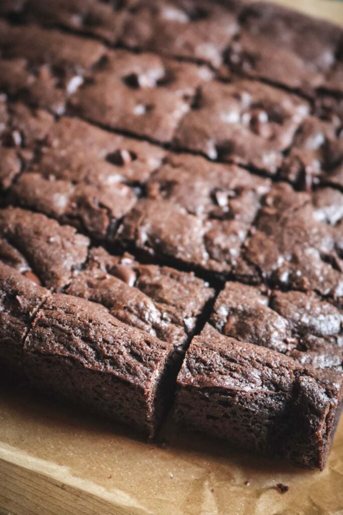 close up view of chocolate chocolate chip cookie bars sliced on parchment paper.