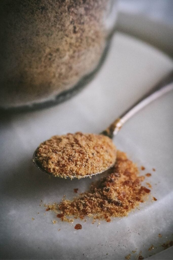 close up view of a metal spoon with homemade caramel sugar made by blending a dry caramel into a powder.