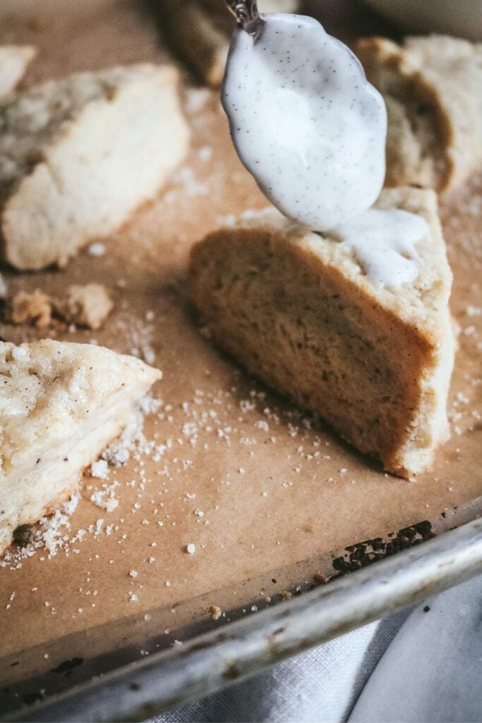 spooning vanilla bean scones with the glaze.